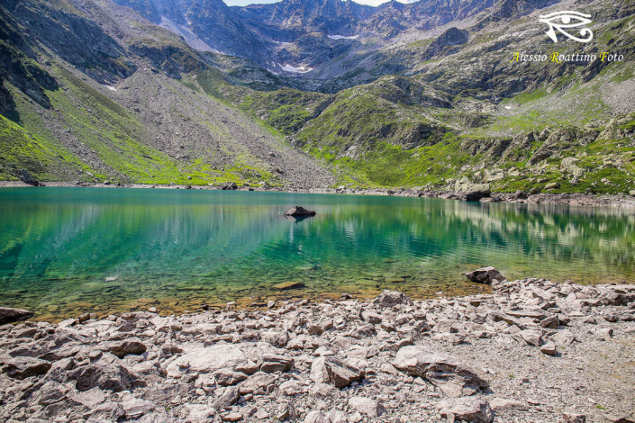 Entracque, lago Brocan ripreso dalla spiaggia con i riflessi sull'acqua delle colline che lo circondano